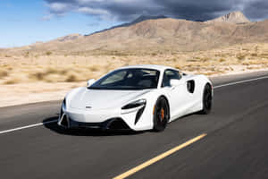 白色McLaren跑車在沙漠高速公路上飛馳，背景有山脈。 — 麥拉倫 壁紙