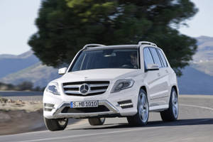 白色Mercedes GLK SUV在山路上行駛，附近有一棵大樹。 — Mercedes-Benz 壁紙