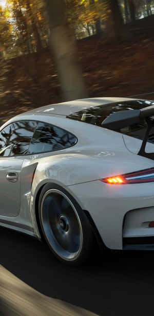 白色保時捷911 GT3 RS在日落時分於秋林中疾馳。 — Pixel 4 壁紙