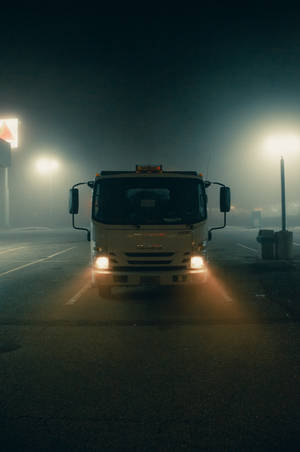 白色卡車車頭燈在夜間黑暗的停車場中劃破霧氣。 — 卡車 壁紙