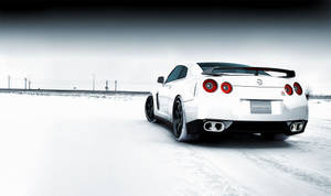 白色日產GT-R跑車在雪路上行駛，冬季風景。 — 日產 壁紙