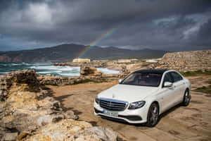 白色豪華車停泊在海岸石徑上，暴風雨天空下出現彩虹 — Mercedes Benz C300 壁紙
