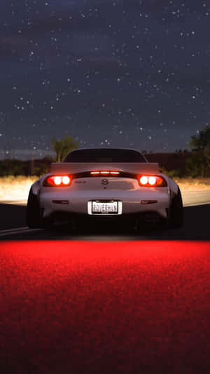 白色跑車配紅色尾燈，在星光燦爛的夜空下駛於發紅光的道路。 — 馬自達 壁紙