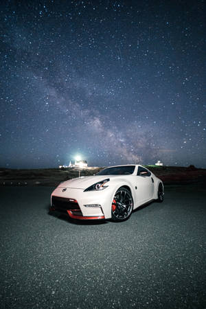 白色跑車停放在星空下，銀河可見。 — 日產 壁紙
