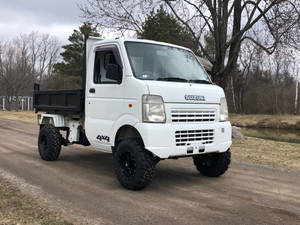 白色鈴木4x4自卸車停泊在溪流和光禿樹木附近的泥土路上。 — 鈴木 壁紙