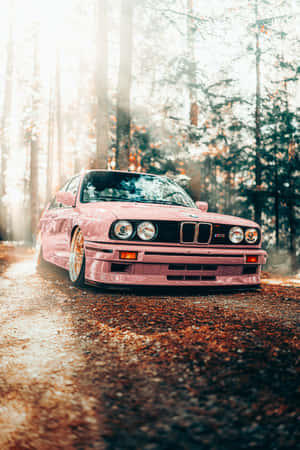 粉紅色BMW E30 M3在林間道路上飄移，金色陽光穿過樹木。 — BMW 動圖 壁紙