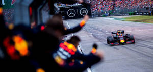 日落時紅牛F1賽車駛過維修站人員。