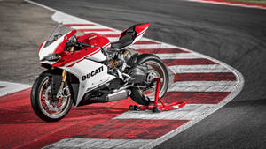 紅白相間的Ducati摩托車在賽道上，帶有紅白相間的賽道邊緣。 — 杜卡迪 GIF 壁紙