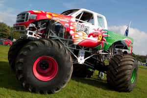 一輛以龍為主題的怪獸卡車，配備巨大輪胎，停在草地上。 — Monster Energy 壁紙
