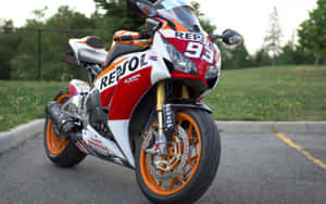 紅色、白色和橙色的Repsol Honda賽車機車停在柏油路上，靠近草地。 — Mercedes Benz C300 壁紙