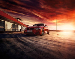 紅色BMW M4跑車在賽道上，夕陽天空戲劇性，輪胎痕清晰可見。