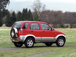 紅色和銀色的緊湊型SUV在草地上行駛，背景有樹木。 — 好看汽車 壁紙
