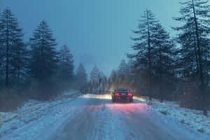 紅色汽車在黃昏時分行駛在穿過松林的白雪道路上。 — MacBook Air 壁紙