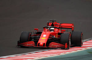 紅色法拉利F1賽車在紅白路緣的賽道上奔馳。 — 紅牛F1 壁紙