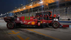 紅色法拉利F1賽車55號夜間停泊在維修區通道，附近有車隊成員。 — 賽車 壁紙