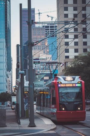 紅色電車穿過市中心，周圍有高樓大廈和建築起重機。 — 休士頓 壁紙