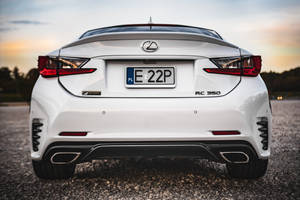 白色Lexus RC 350 F Sport在日落時分碎石路上的後視圖。 — 白色 iPhone 壁紙