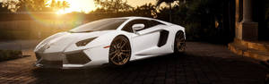 白色藍寶堅尼 Aventador 停放在金色夕陽下的磚砌車道上。 — 跑車 壁紙