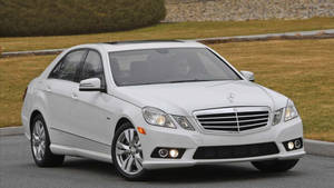 白色賓士E-Class轎車停在靠近草地和灌木的鋪砌道路上。 — Mercedes Benz C300 壁紙