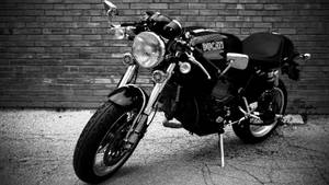 一輛Ducati摩托車停在磚牆旁裂開的柏油路面上。 — 杜卡迪 GIF 壁紙
