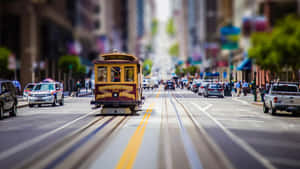 一輛黃色纜車在繁忙的城市街道上行駛，有汽車和行人。 — 舊金山 壁紙