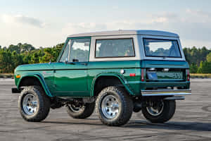 綠色經典福特Bronco SUV停在瀝青路面上，背景有樹木。 — 福特野馬越野車 壁紙