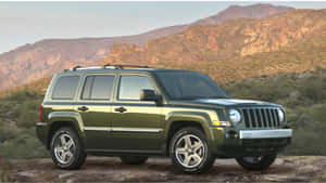 綠色Jeep Patriot在日落時停泊在沙漠岩石上，以山脈為背景。 — 吉普 壁紙