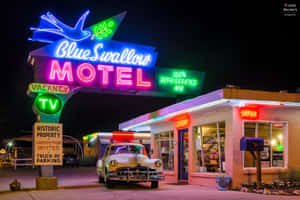夜晚在霓虹燈照亮的Blue Swallow Motel停泊的老爺車。 — 80年代美學 壁紙