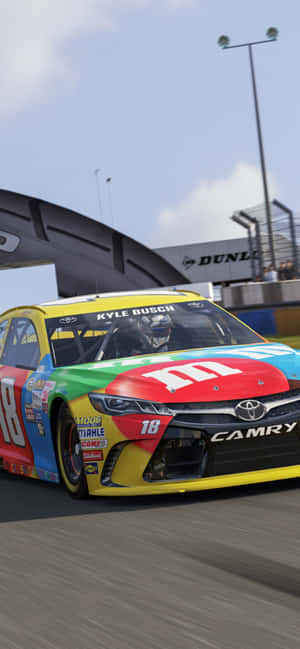 Kyle Busch在賽道上駕駛一輛色彩繽紛的M&M's Toyota Camry賽車。 — Pixel 10 Pro XL 壁紙