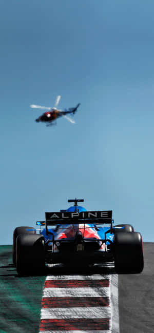 藍色Alpine F1賽車在賽道上奔馳，直升機在上空。 — iPhone 16 Pro Max 壁紙