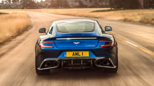 藍色Aston Martin Vanquish在日落時分的鄉村道路上疾馳。 — 阿斯頓維拉 壁紙
