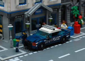 LEGO警車停放在警察局外，配有警員和街道元素。 — 高譚 壁紙