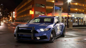 藍色警用Mustang停在潮濕城市街道上，夜晚有霓虹燈招牌。 — 警察 GIF 壁紙