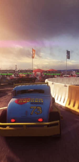 藍色賽車編號73在紫色和橙色天空下於黃昏時分在賽道上疾馳。 — Pixel 4 壁紙