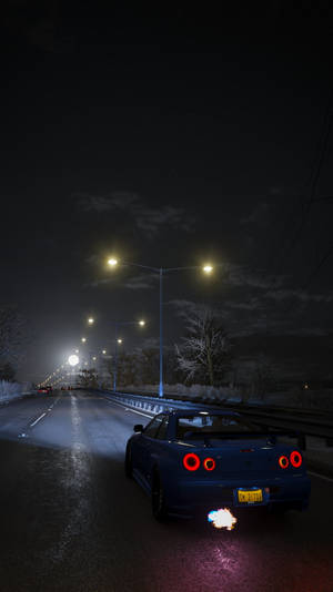 藍色跑車夜晚在雪路上行駛，有街燈照明 — 極限競速 地平線 4 壁紙
