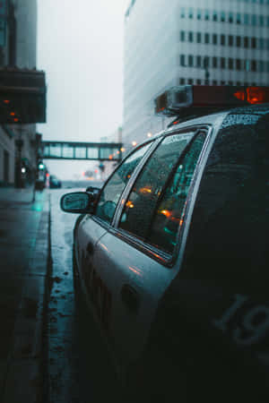 警車停泊在雨夜的城市街道上，濕漉漉的路面和閃爍的燈光。 — 小米平板 7S Pro 12.5 壁紙