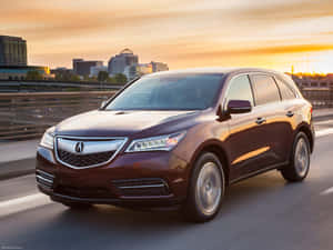 日落時分在高速公路上行駛的酒紅色Acura SUV，背景是城市天際線。 — Acura 壁紙