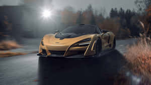 金色McLaren在潮濕森林道路上疾馳，伴隨秋樹和陽光。 — 汽車 壁紙