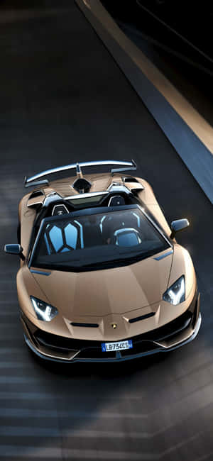 金色藍寶堅尼 Aventador SVJ Roadster 在賽道上高速行駛。 — iPhone 17 Pro 壁紙