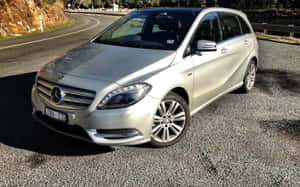 銀色 Mercedes-Benz 旅行車停放在蜿蜒道路附近的碎石路上。 — Steam Deck 壁紙