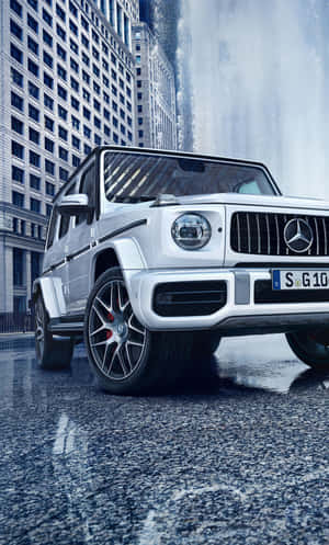 銀色 Mercedes G-Class SUV 停在瀑布和摩天大樓附近的濕漉漉街道上。 — Mercedes Benz C300 壁紙