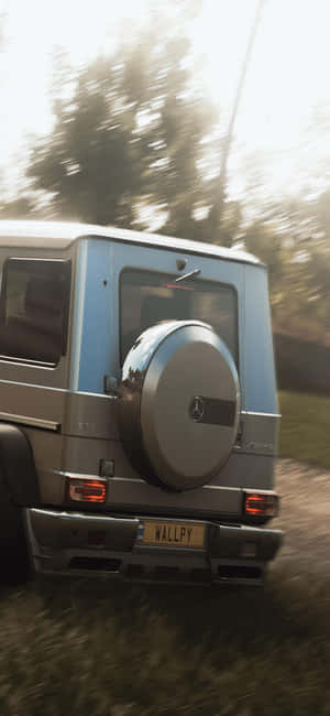 銀色 Mercedes G-Wagen 在日落時分穿越森林。 — iPhone 17e 壁紙
