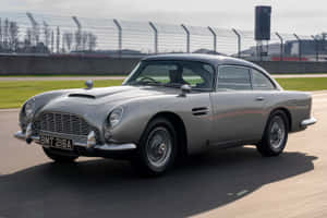 銀色Aston Martin DB5在賽道上疾馳，駕駛員可見。 — Surface Laptop 壁紙