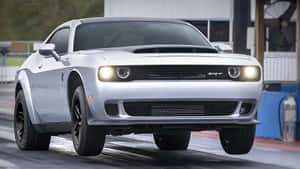銀色Dodge Challenger SRT在潮濕的直線加速賽道上亮著車頭燈加速行駛。 — 道奇挑戰者 壁紙