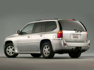 銀色GMC Envoy SUV從後方四分之三角度拍攝的攝影棚照片。 — 低飽和 壁紙