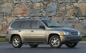銀色GMC Envoy SUV停放在鋪砌表面上的石牆旁。 — Steam Deck OLED 壁紙