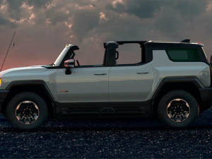 暮色中碎石上的銀色電動Hummer EV，伴隨著色彩繽紛的雲彩。 — 卡車 壁紙