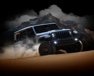 銀色Jeep Rubicon夜間在沙漠沙地上行駛，背景有山脈。 — 吉普 壁紙