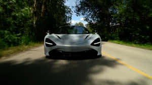 銀色McLaren在森林道路上高速行駛，帶有動態模糊效果。 — 汽車 壁紙