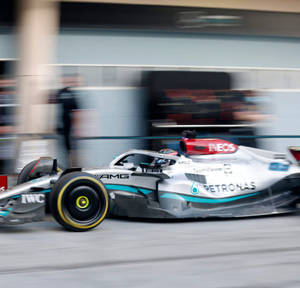一輛高速F1賽車在街道賽道上飛馳，帶有動態模糊效果。 — F1 iPhone 壁紙